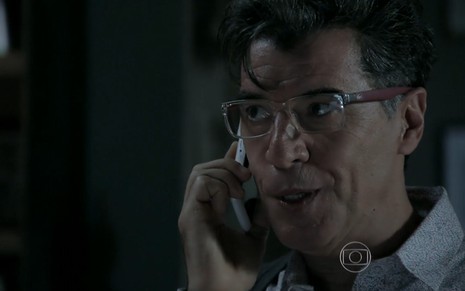 Paulo Betti grava com óculos de grau e celular no ouvido como Téo Pereira, seu personagem de Império