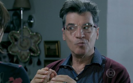 Paulo Betti grava de camisa azul, casaco vermelho e óculos de grau com expressão de travesso como Téo de Império
