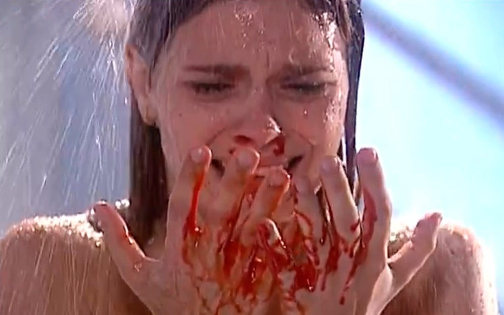 Carolina Dieckmann caracterizada como Camila em Laços de Família: aos prantos, atriz olha para as mãos cheias de sangue