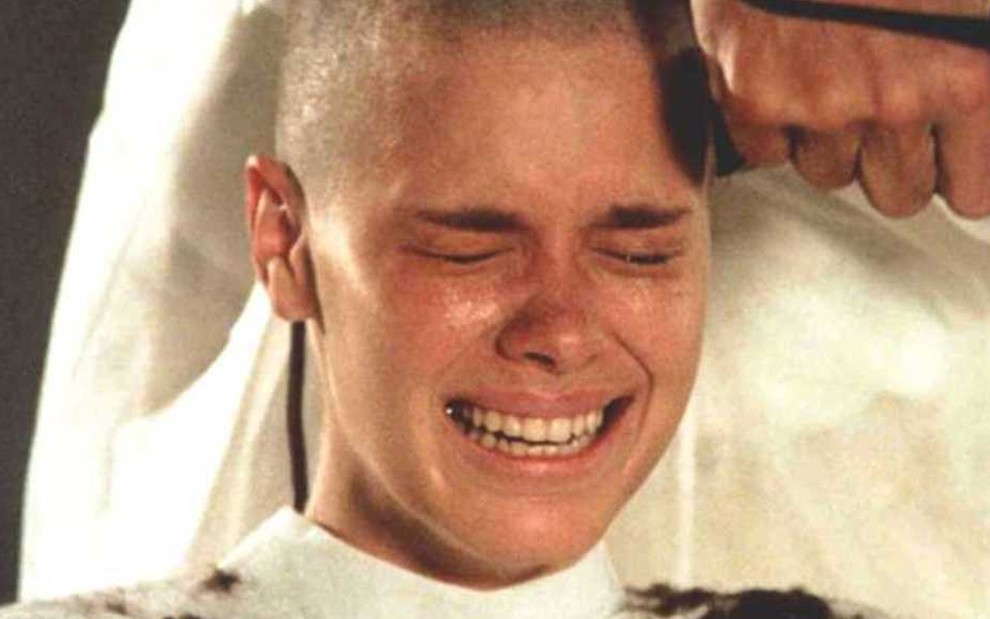 A atriz Carolina Dieckmann com os cabelos raspados por uma máquina chora caracterizada como a Camila em Laços de Família