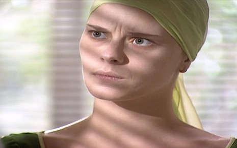 A atriz Carolina Dieckmann, com expressão de dúvida e lenço na ca bela, grava cena como Camila na novela Laços de Família