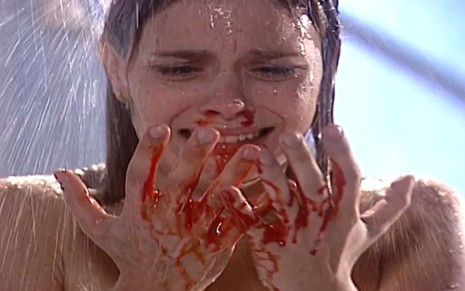 A atriz Carolina Dieckmann com expressão de pânico ao olhar sangue nas mãos em cena como Camila em Laços de Família