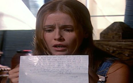 A atriz Deborah Secco, com uma carta na mão e expressão de choque, em cena como Íris em Laços de Família
