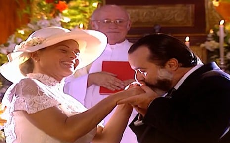 Vera Fischer grava, de noiva, ao lado de Tony Ramos em altar como Helena e Miguel na novela Laços de Família