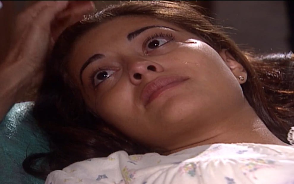 A atriz Juliana Paes grava de camisola, deitada e chorando como Rita, sua personagem em Laços de Família
