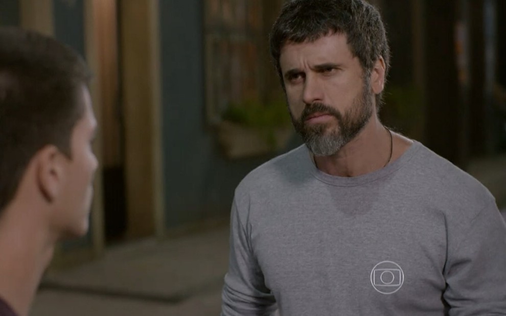 Eriberto Leão grava de camiseta de manga longa cinza e expressão brava conversando com Arthur Aguiar, de costas na foto