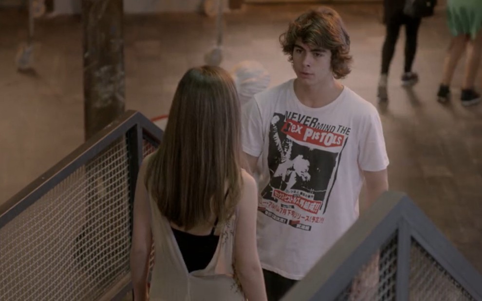 Rafael Vitti grava com camiseta estampada ao lado de Bruna Hamú, de costas na foto como Pedro e Bianca de Malhação