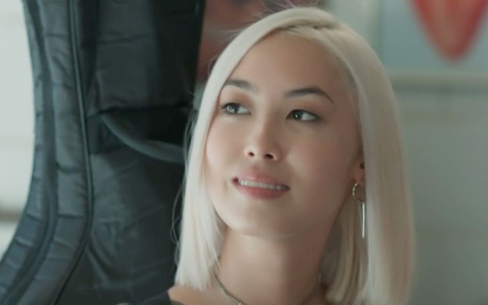 A personagem Tina (Ana Hikari) olha sorridente em cena da novela Malhação - Viva a Diferença, da Globo; atriz está de cabelo curto e loiro platinado