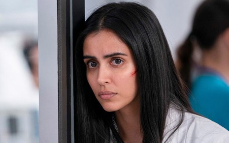Desolada e com um corte na bochecha, Parveen Kaur escora a cabeça em um batente de um hospital na série Manifest 