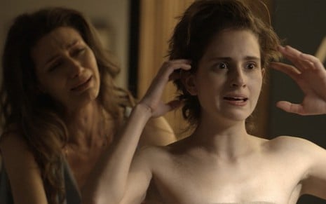A atriz Maria Fernanda Cândido chora desesperada ao fundo como Joyce enquanto Carol Duarte, ainda de Ivana, mexe nos cabelos em A Força do Querer