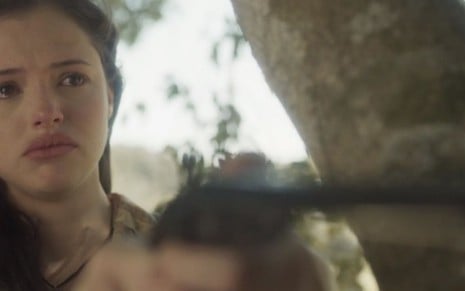 A atriz Agatha Moreira segura uma arma e chora como a personagem Domitila em cena de Novo Mundo, da Globo