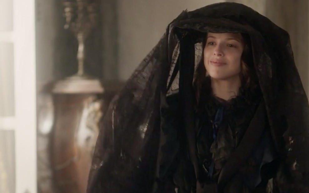 A atriz Agatha Moreira usa uma roupa preta com um grande véu que cobre o corpo inteiro caracterizada como a Domitila de Novo Mundo