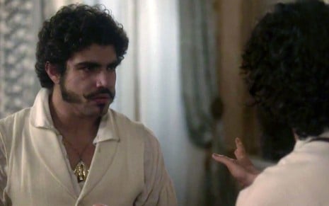 O ator Caio Castro, com lágrimas nos olhos como Pedro, é impedido de passar por Caco Ciocler, de braços abertos como Peter, em Novo Mundo