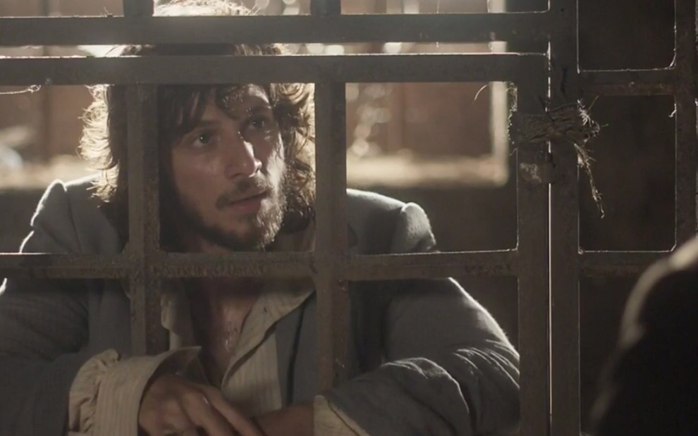 O ator Chay Suede grava cena encarcerado, agarrado a grades, caracterizado como o personagem Joaquim de Novo Mundo
