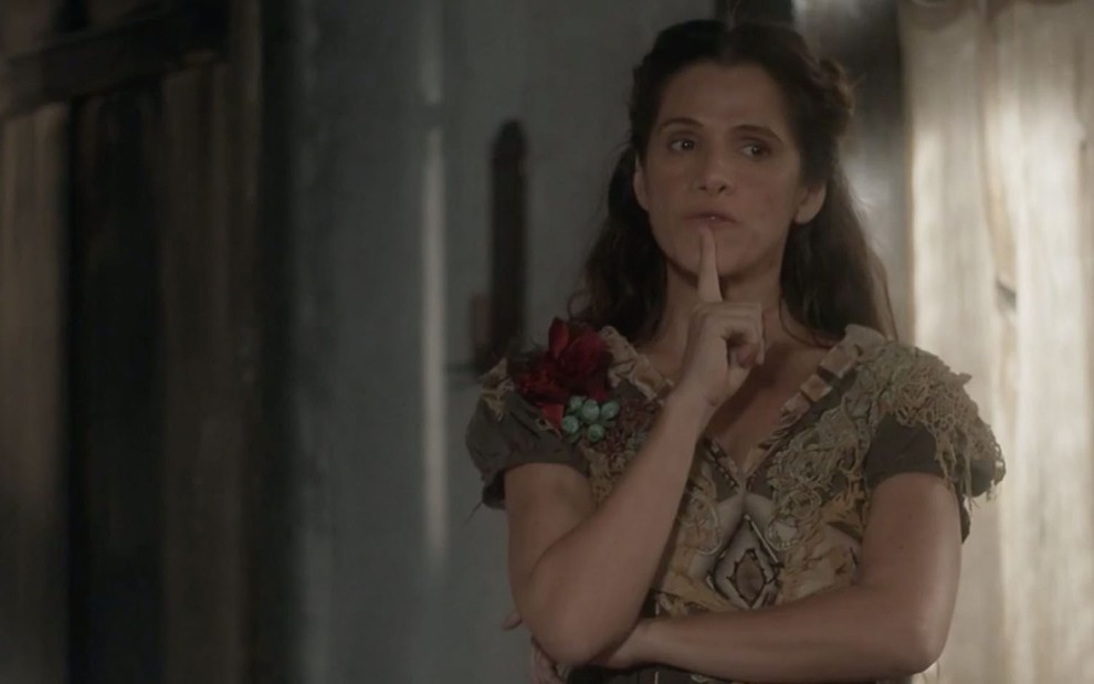 A atriz Ingrid Guimarães leva o dedo indicador ao queixo no sinal de que está pensando caracterizada como a Elvira de Novo Mundo