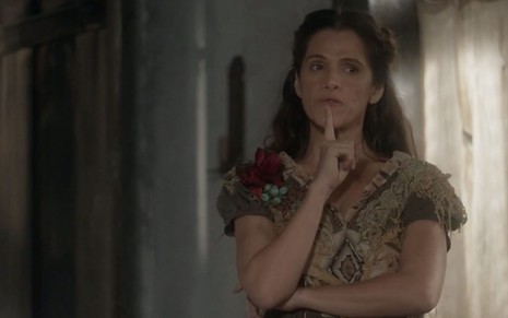A atriz Ingrid Guimarães leva o dedo indicador ao queixo no sinal de que está pensando caracterizada como a Elvira de Novo Mundo