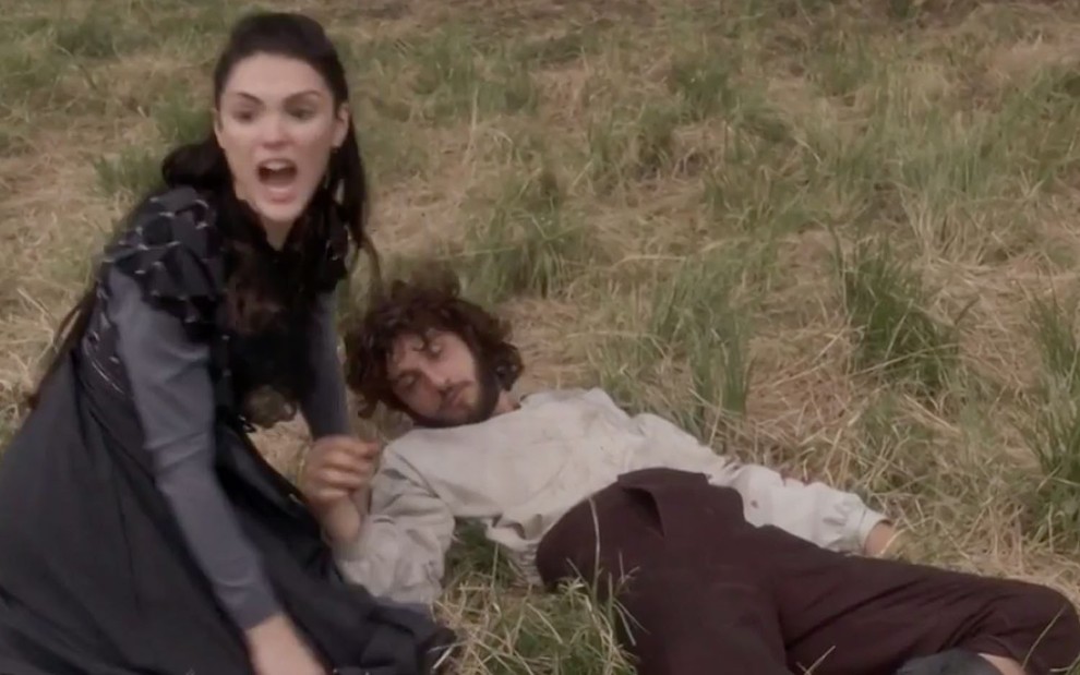 A atriz Isabelle Drummond, a Anna, grita enquanto Chay Suede está deitado como Joaquim em cena de Novo Mundo