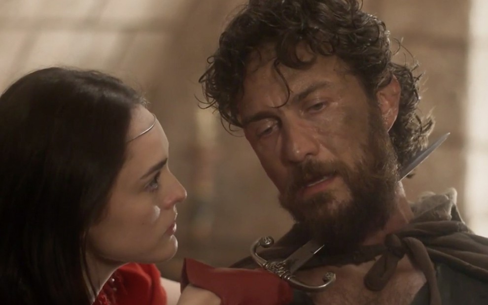 A atriz Isabelle Drummond como Anna segura um punhal contra a garganta de Gabriel Braga Nunes, o Thomas, em cena de Novo Mundo