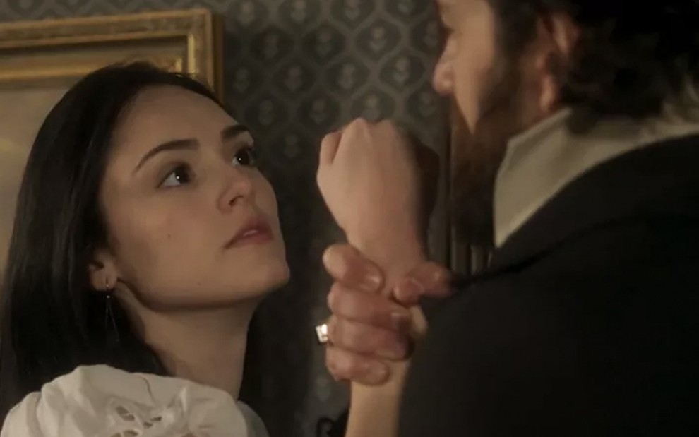 A atriz Isabelle Drummond caracterizada como Anna tem o braço segurado por Gabriel Braga Nunes, o Thomas, de costas em cena de Novo Mundo