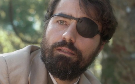 O ator Ricardo Pereira com expressão perplexa usa um tapa olho do lado direito caracterizado como Ferdinando em cena de Novo Mundo