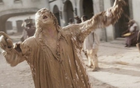 O ator Roberto Cordovani sujo com uma substância marrom que imita fezes caracterizado como Sebastião em cena de Novo Mundo