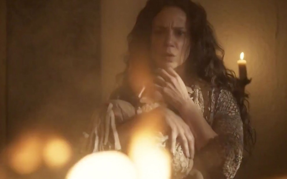 A atriz Vanessa Gerbelli caracterizada como a personagem Amália cercada pelo fogo em cena de Novo Mundo