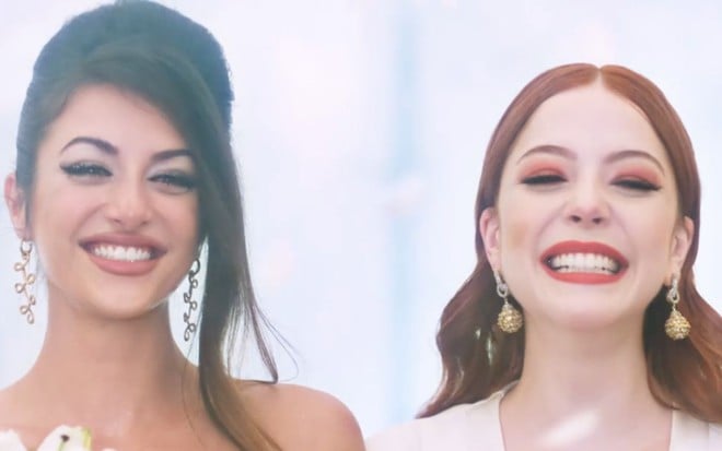 As atrizes Anaju Dorigo (à esq.) e Bia Arantes (dir.) sorriem como o casal Camila e Valéria na novela Órfãos da Terra, da Globo