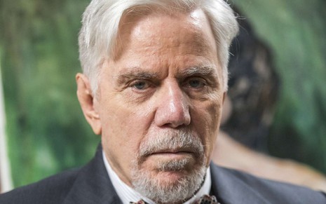 O ator Reginaldo Faria, de terno e gravata, exibe expressão de bravo em imagem de divulgação da Globo