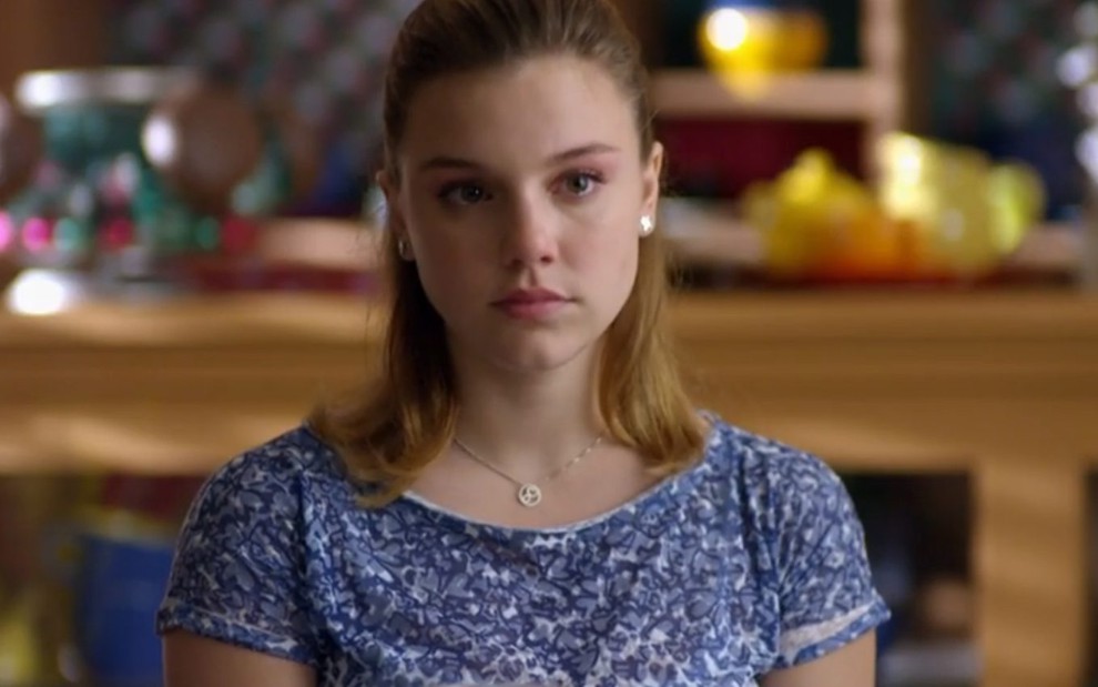 A atriz Alice Wegmann usa uma blusa azul estampada e tem semblante sério em cena como Sofia em A Vida da Gente