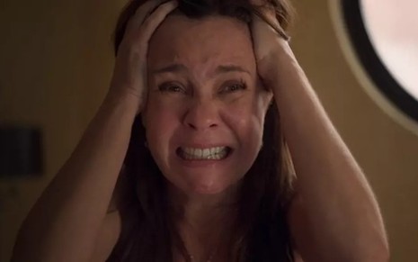 A atriz Adriana Esteves, com as mãos na cabeça e expressão de sofrimento, em cena como Thelma em Amor de Mãe