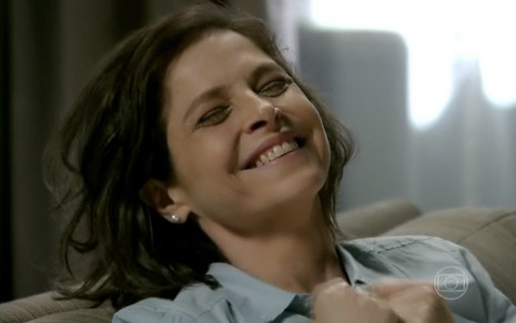 A atriz Drica Moraes exibe os cabelos bagunçados e um sorriso no rosto em cena como Cora da novela Império