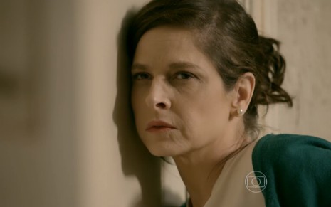 A atriz Drica Moraes, com a cabeça colada em uma porta, em cena como Cora em Império
