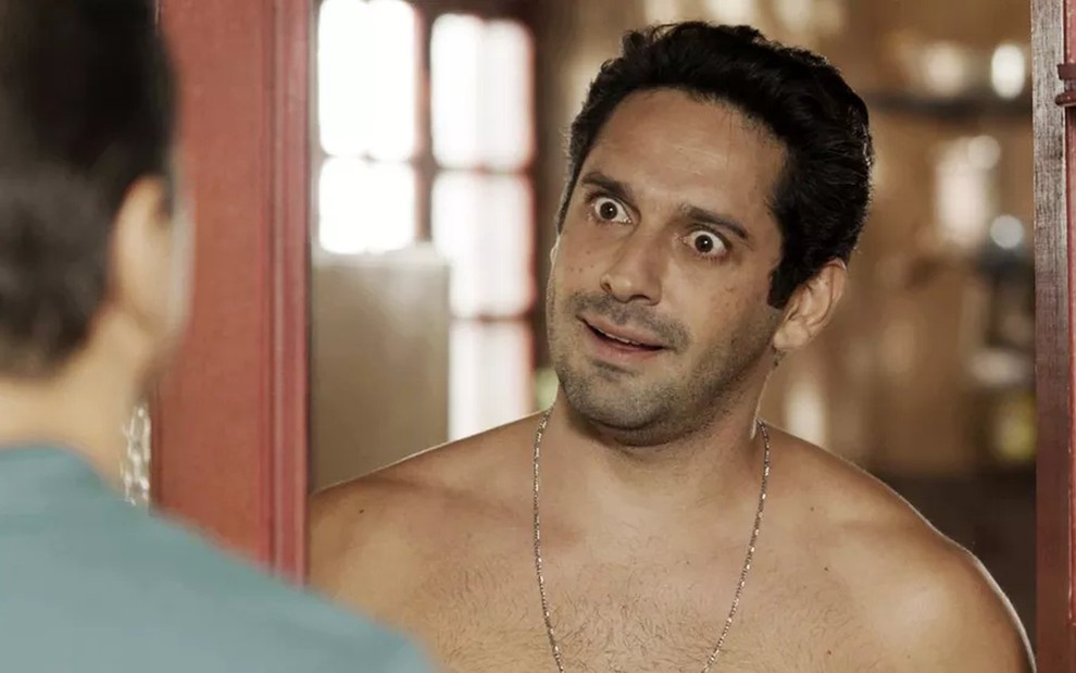 O ator João Baldasserini, sem camisa, com expressão de surpresa em cena como Zezinho em Salve-se Quem Puder
