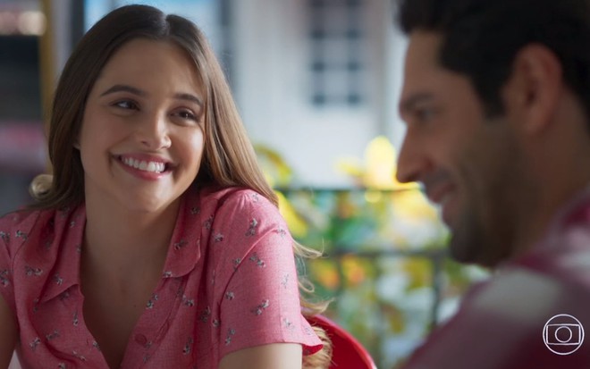 A atriz Juliana Paiva, com um enorme sorriso no rosto, em cena como Luna em Salve-se Quem Puder; ela contracena com João Baldasserini