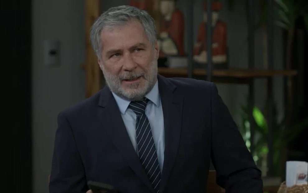 O ator Leopoldo Pacheco, de terno e gravata em cena de conversa como Hugo em Salve-se Quem Puder