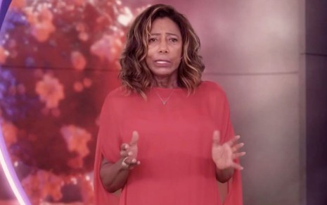 A apresentadora Glória Maria veste vermelho na Retrospectiva 2020 da Globo, exibida na noite de terça (29); uma foto do vírus da Covid-19 aparece no telão ao fundo do estúdio
