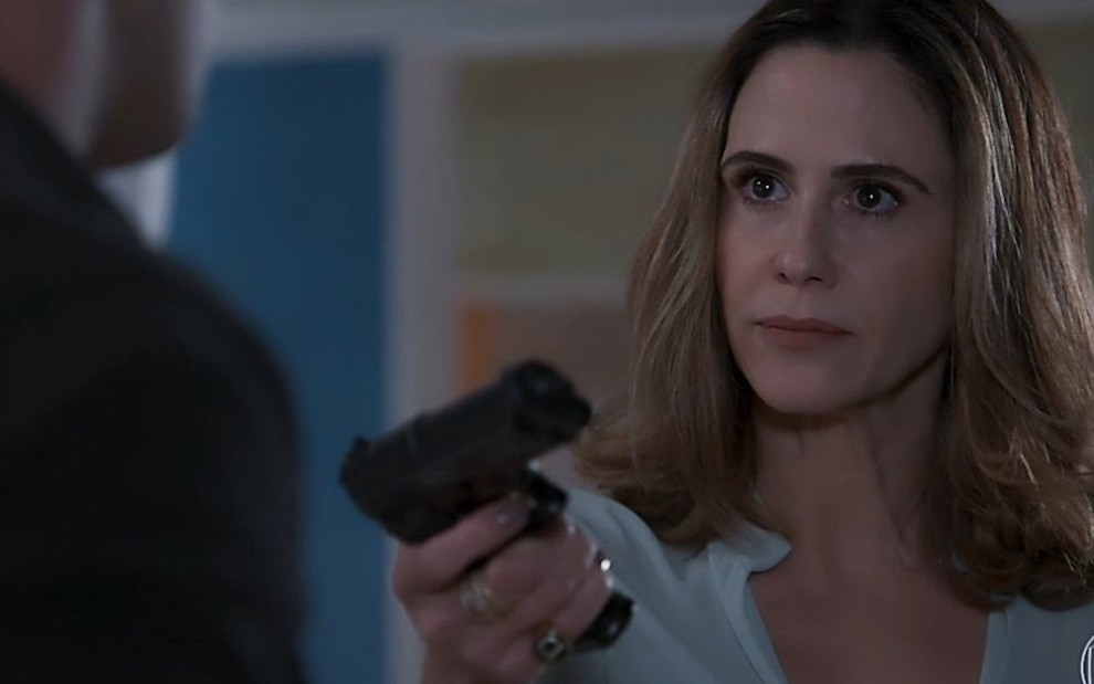 A atriz Guilherme Guinle segura revólver em cena da novela Salve-se Quem Puder, da Globo, na qual interpreta Dominique