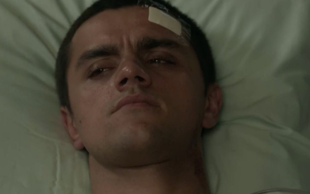 O ator Felipe Simas aparece deitado em uma cama de hospital como o personagem Téo da novela Salve-se Quem Puder, da Globo