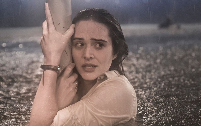 A personagem Luna (Juliana Paiva), de Salve-se Quem Puder, se agarra em um poste em cena de furacão