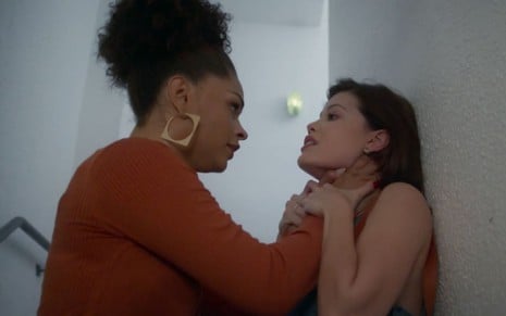 Juliana Alves e Vitória Strada em cena de Salve-se Quem Puder: Renatinha segura Kyra pelo pescoço e a pressiona em parede