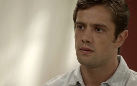 O ator Rafael Cardoso usa uma camisa clara e olha para a direita em cena da novela Salve-se Quem Puder, da TV Globo