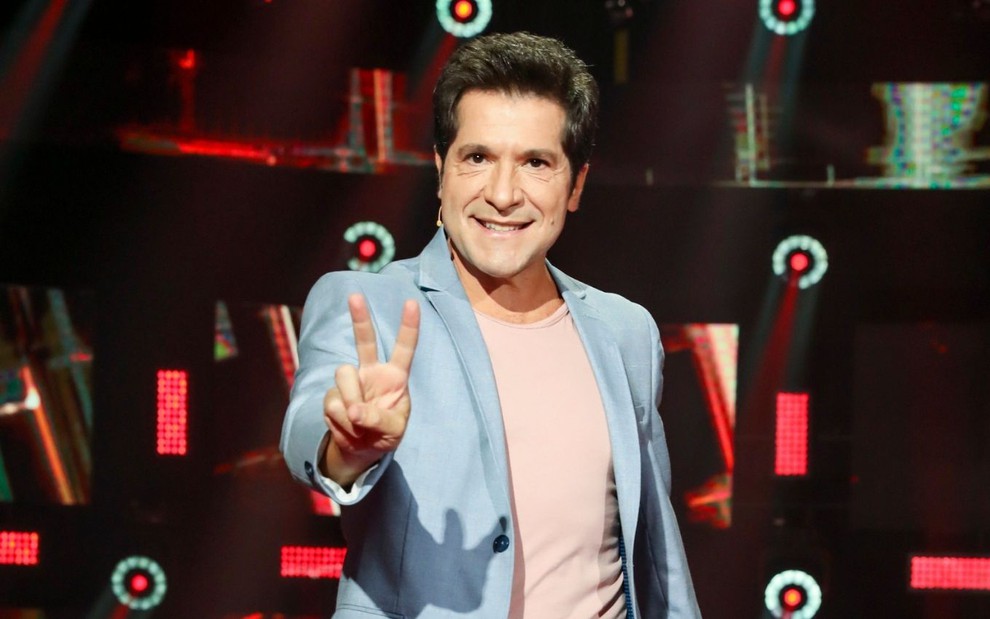 Daniel faz um sinal de V com a mão direita no palco do The Voice+, da Globo