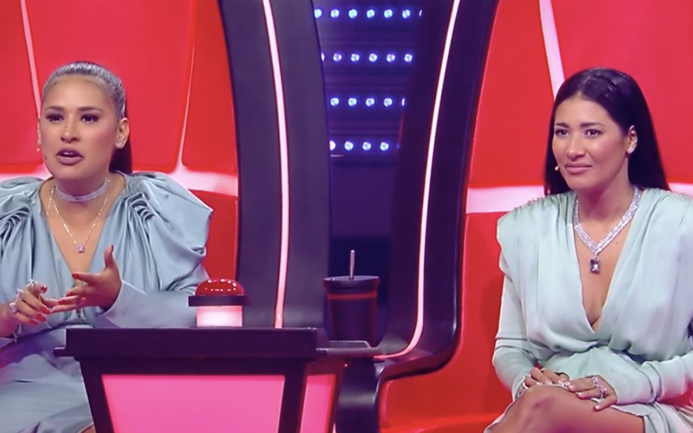 Simone e Simaria sentadas na cadeira vermelha do The Voice Brasil após rejeitar candidato