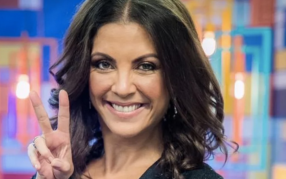 A apresentadora e escritora Thalita Rebouças faz a letra V com os dedos no cenário do The Voice Kids