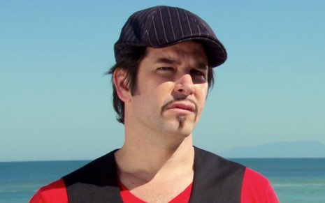 Murilo Benício caracterizado como Ariclenes em cena de Ti Ti Ti: vestido como Victor Valentim, ator está na praia e posa para foto