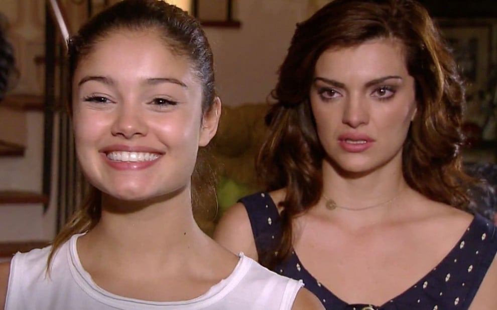 Sophie Charlotte e Mayana Neiva em cena de Ti Ti Ti, enquanto Sophie sorri, Mayana chora em segundo plano; ambas olham para alguém fora do quadro.