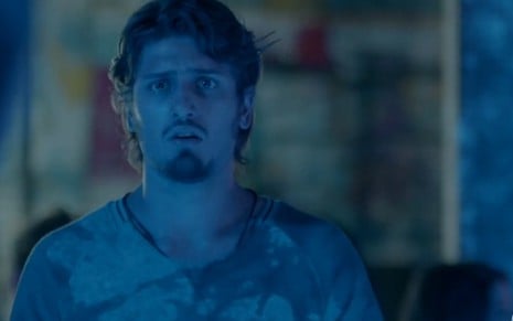 Rafael (Daniel Rocha) com cara de surpresa e uma luz azul de boate em cena de Totalmente Demais