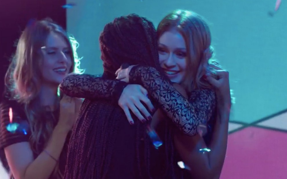 A atriz Marina Ruy Barbosa em cena de Totalmente Demais: personagem Eliza abraça outras candidatas do concurso