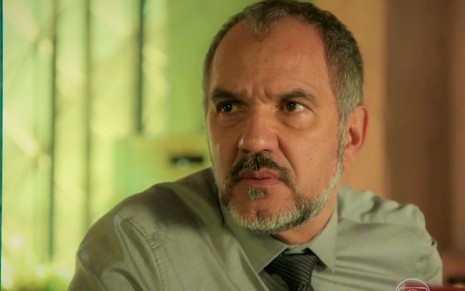 O ator Humberto Martins com expressão séria em cena de Totalmente Demais em que usa camisa verde com gravata escura