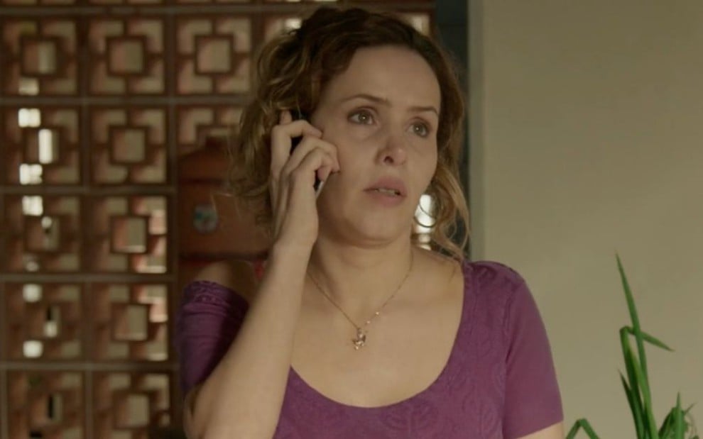 Leona Cavalli caracterizada como Gilda em Totalmente Demais: personagem usa uma blusa roxa e fala ao celular